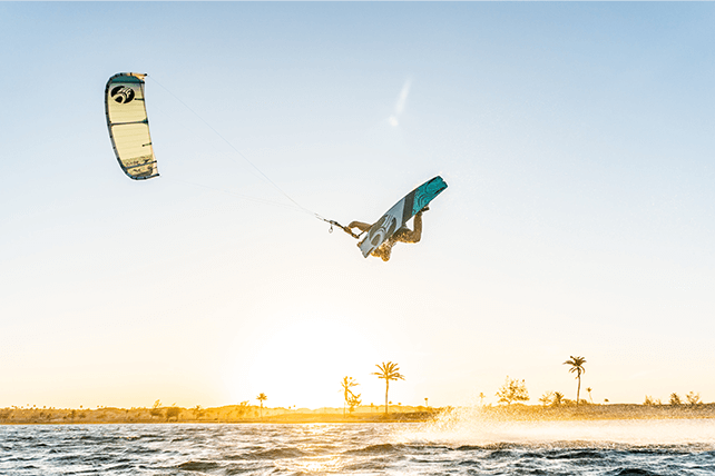 Flight of a kite surfer at sunrise