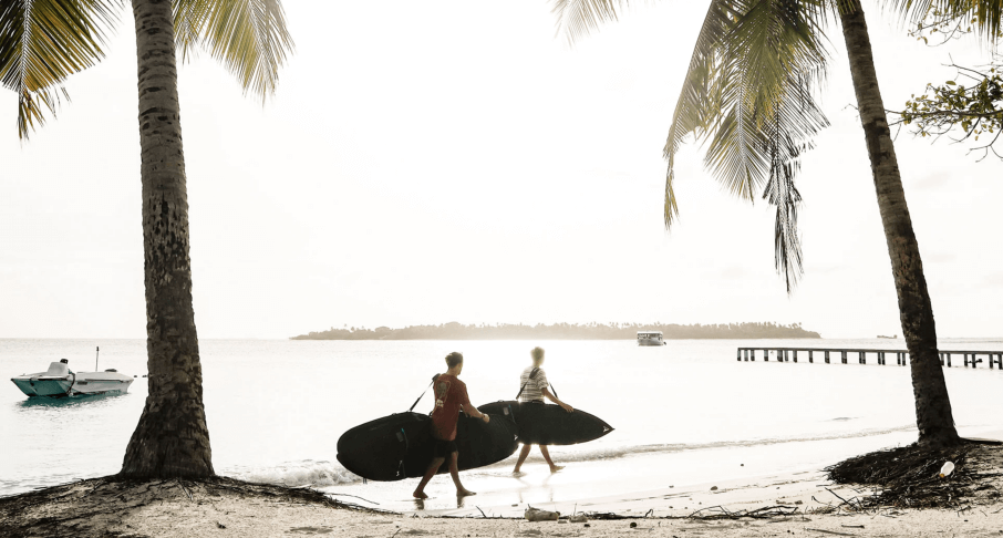 zwei Surfer vor der Surfsession mit Boardbags am Strand